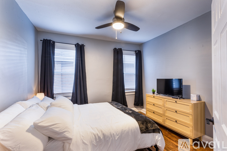 A bedroom with a bed, dresser, and television.