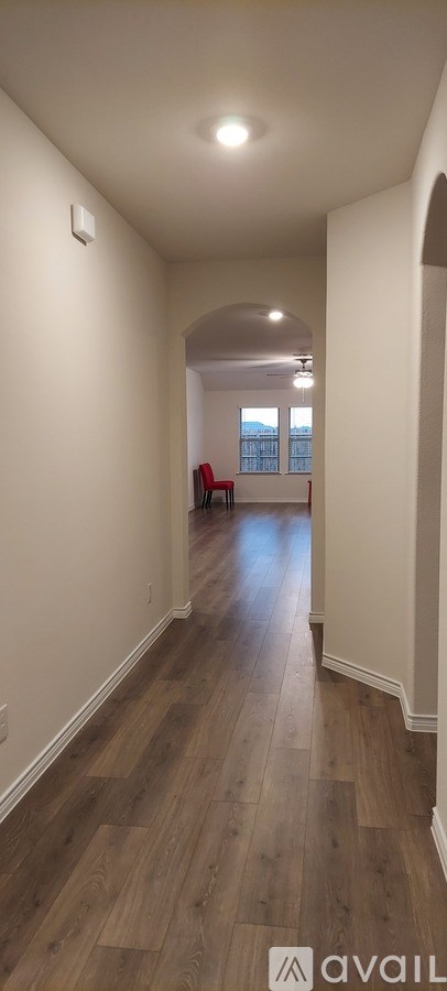 A long hallway with wood floors and white walls.
