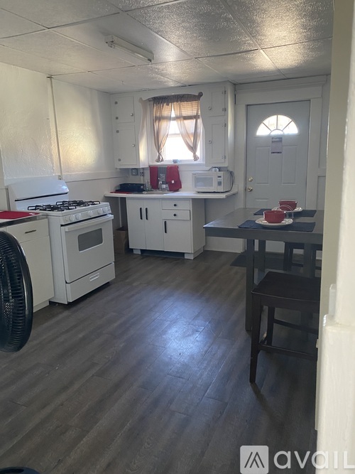 A kitchen with white appliances and wooden floors.