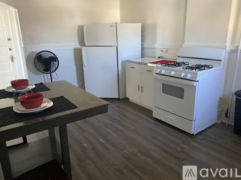 A kitchen with a stove, refrigerator, and a table with a red bowl on it.