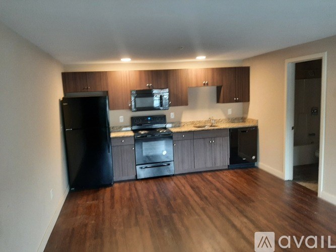 A kitchen with black appliances and wooden floors.