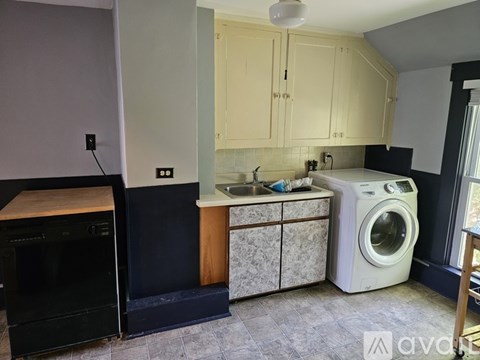 A kitchen with a black oven and a white washing machine.