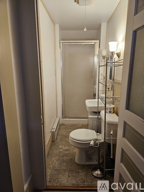 A white toilet is in a small bathroom with a shower.