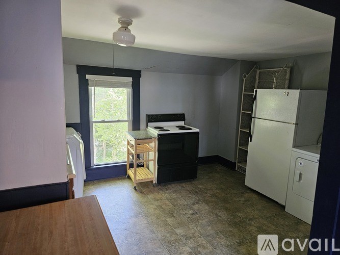 A room with a desk, a window, and a white refrigerator.