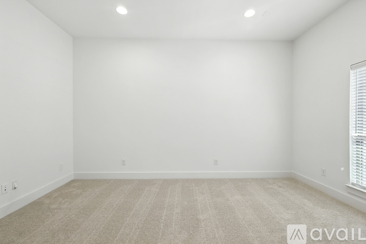 A room with a carpeted floor and a window with blinds.