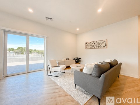 A living room with a grey couch, a white chair, and a small table with a plant on it.
