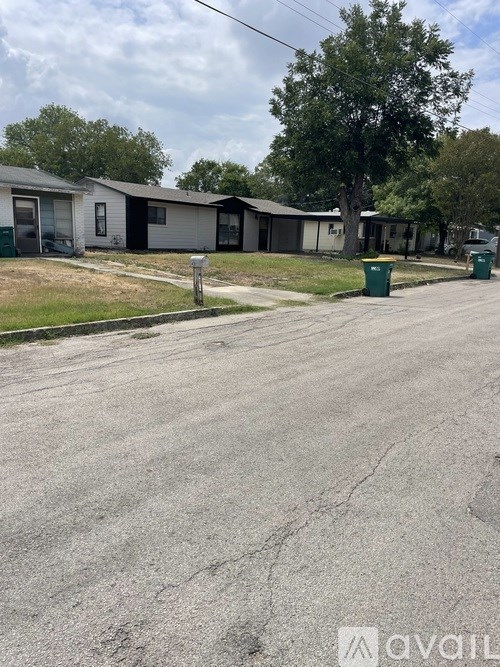 A street view of a residential area with houses and trees.