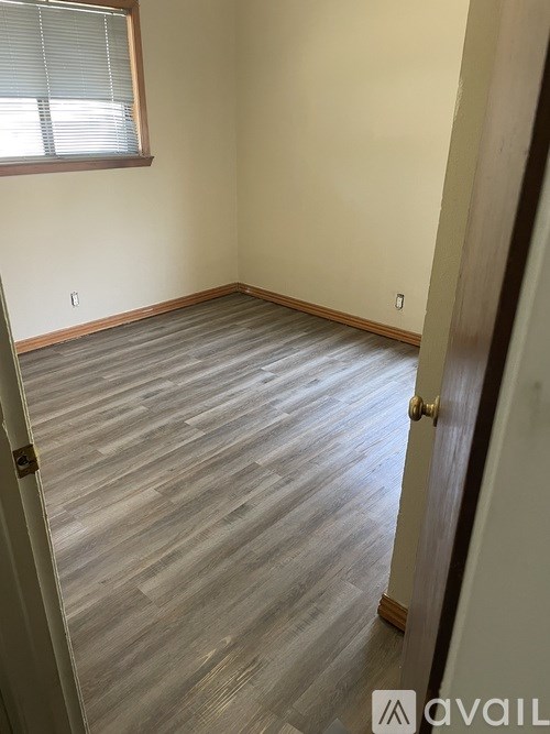 A room with a wooden floor and a door on the left side.