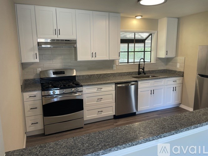 A kitchen with white cabinets and a granite countertop.