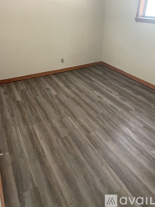 A room with wooden flooring and a window.