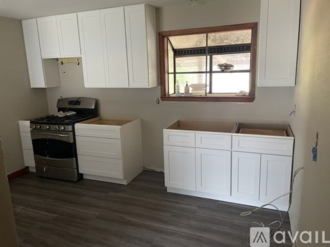 A kitchen with white cabinets and a window.