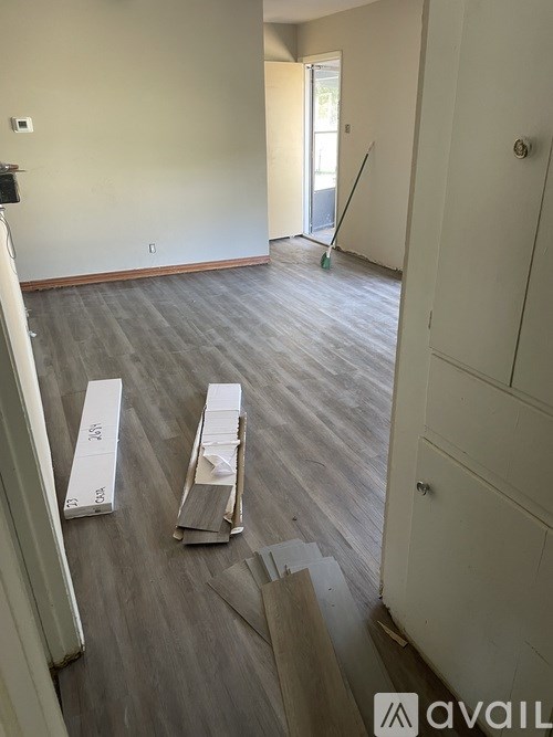 A room with wooden flooring and a white door is shown.
