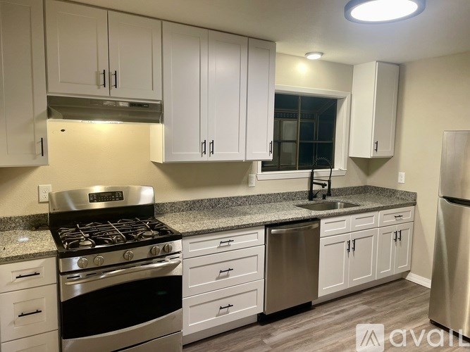 A kitchen with white cabinets and a stainless steel refrigerator.