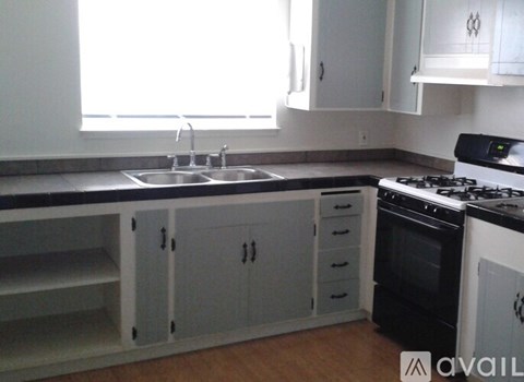 A kitchen with a black stove top oven and a white sink.