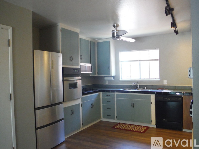 A kitchen with a refrigerator, oven, and sink.
