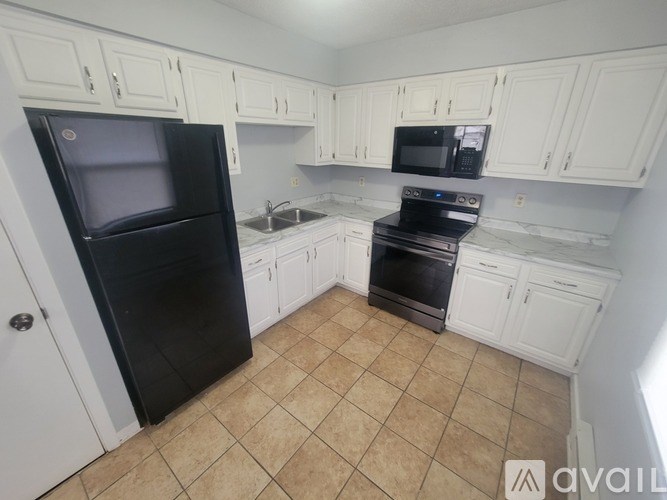 A kitchen with black appliances and white cabinets.