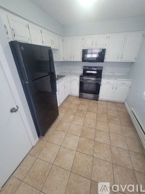 A kitchen with black appliances and white cabinets.
