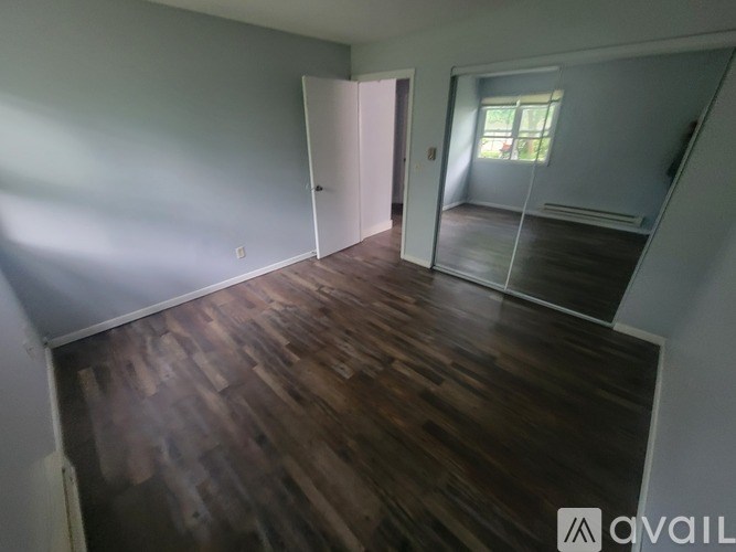 A room with wooden flooring and a sliding glass door leading to a balcony.