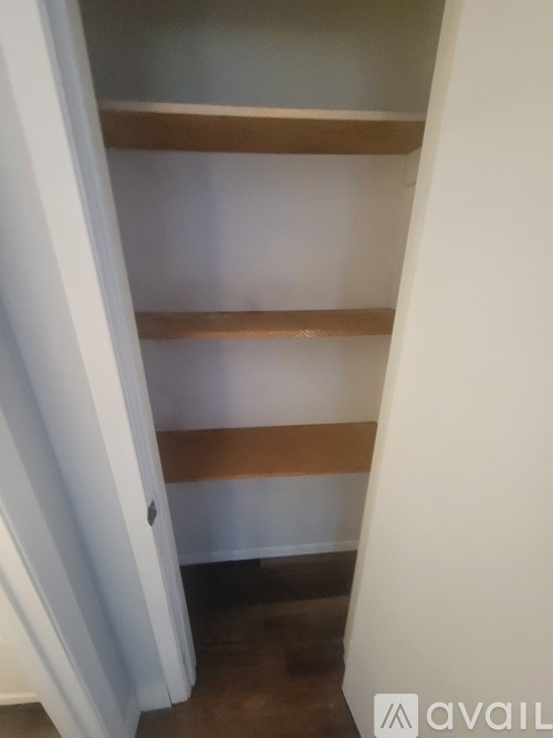 A white door is open to a hallway with a brown shelf.