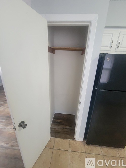 A black refrigerator is in a kitchen next to a white door.