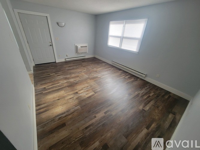 A room with wooden flooring and a window with blinds.