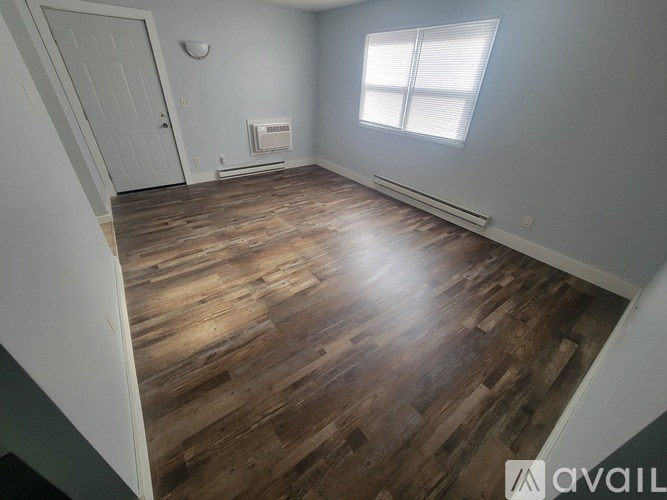 A room with wooden flooring and a window with blinds.