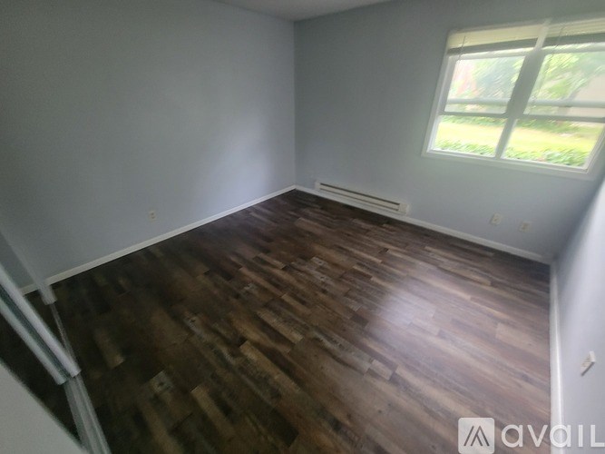 A room with wooden flooring and a window letting in natural light.