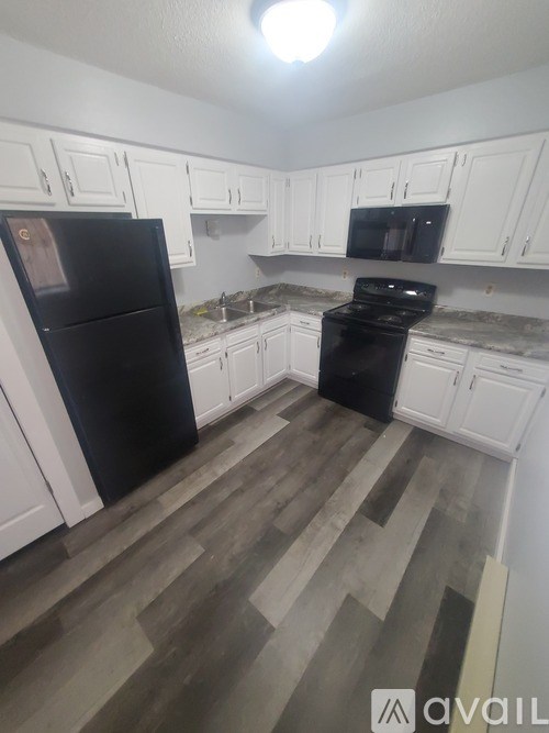 A kitchen with black appliances and white cabinets.