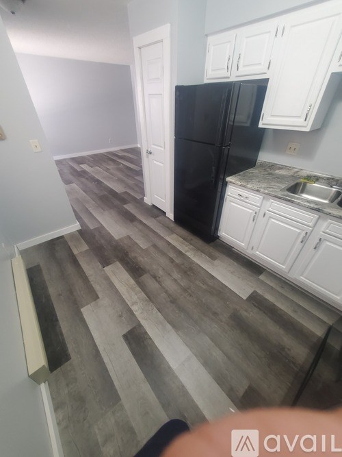 A kitchen with a black fridge and white cabinets.