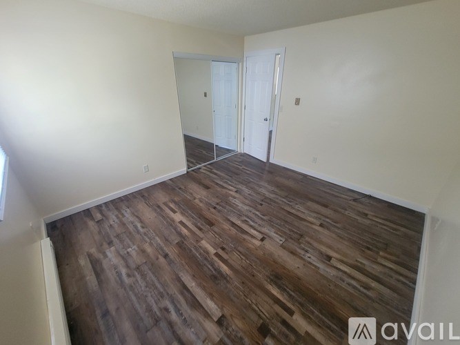 A room with wooden flooring and a window with blinds.