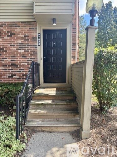 A black door is at the end of a wooden staircase.