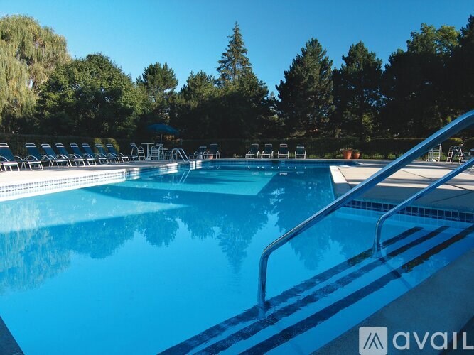 A pool with a blue water and chairs around it.