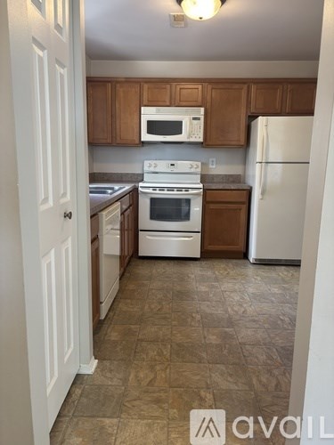 A kitchen with white appliances and brown cabinets.
