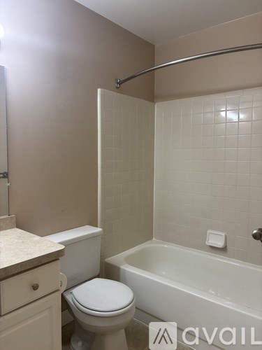 A white toilet sits next to a white bathtub in a bathroom.