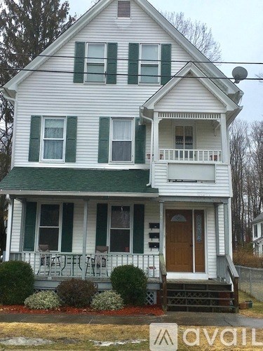 A two-story house with a balcony and a brown door.