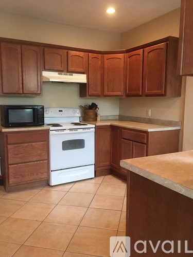 A kitchen with brown cabinets and white appliances.