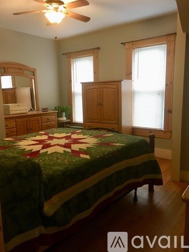 A bedroom with a bed, dresser, mirror, and window.