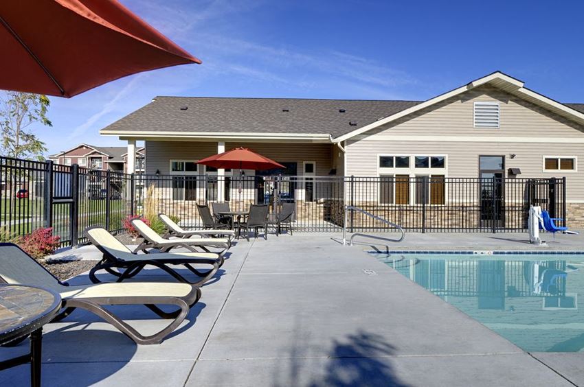 Copper Creek Apartments | Poolside Lounge Chairs Pool with lounge chairs andApt building in backgroundApartments in Colorado Springs, Co Copper Creek Apartments