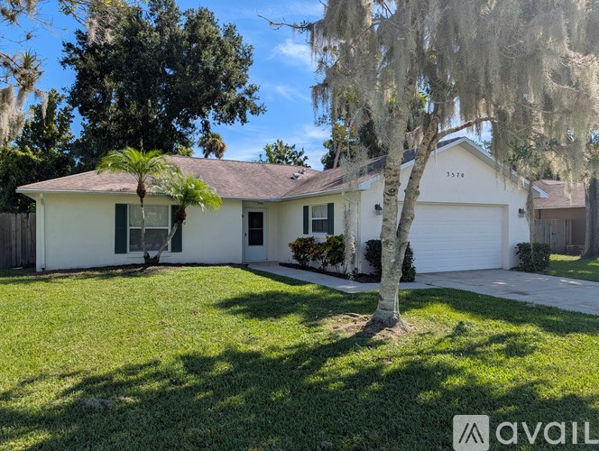 A white house with a green door and a tree in front.