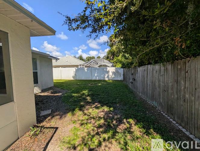 A backyard with a wooden fence and a white house.
