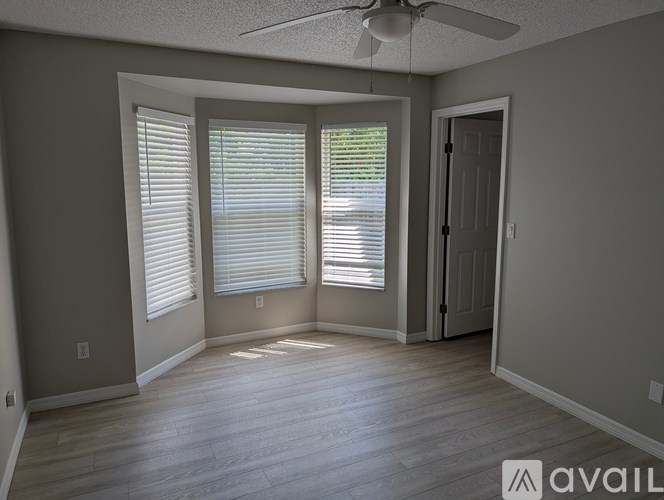 A room with a ceiling fan and two windows with blinds.