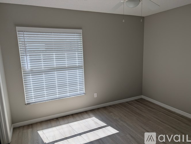 A room with a window covered by white blinds and a fan on the ceiling.