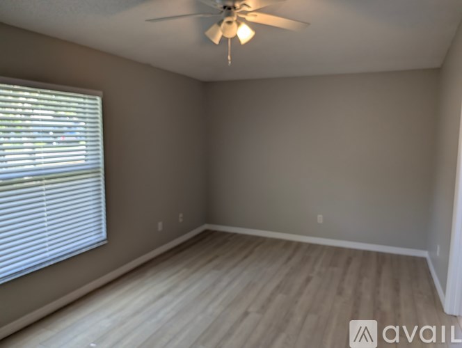 A room with a ceiling fan and a window with blinds.