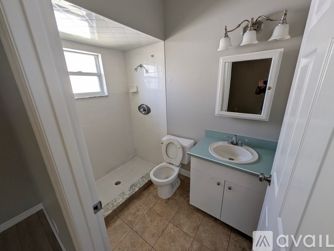 A bathroom with a toilet, sink, and mirror.