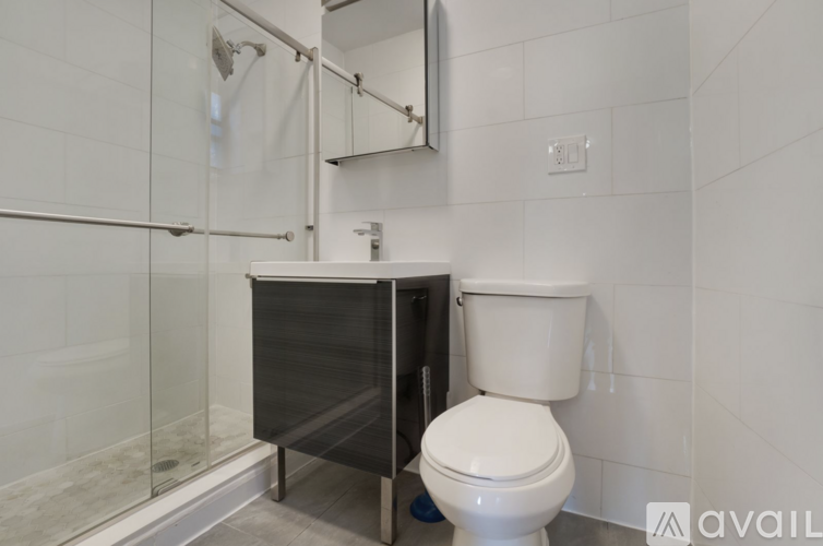A white toilet sits next to a walk-in shower in a bathroom.