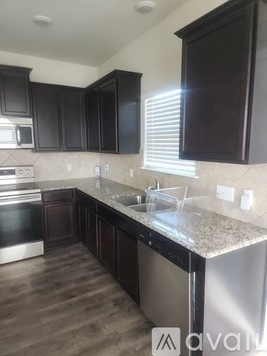 A kitchen with dark brown cabinets and a granite countertop.