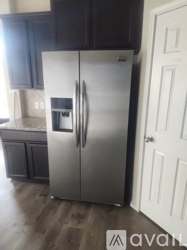 A stainless steel refrigerator stands in a kitchen.