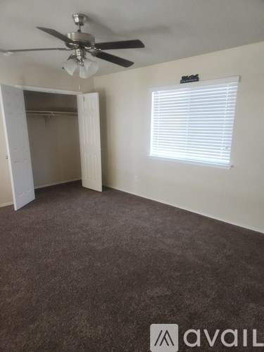 A room with a ceiling fan and a window with blinds.