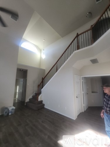 A man is standing in a large empty room with a staircase.