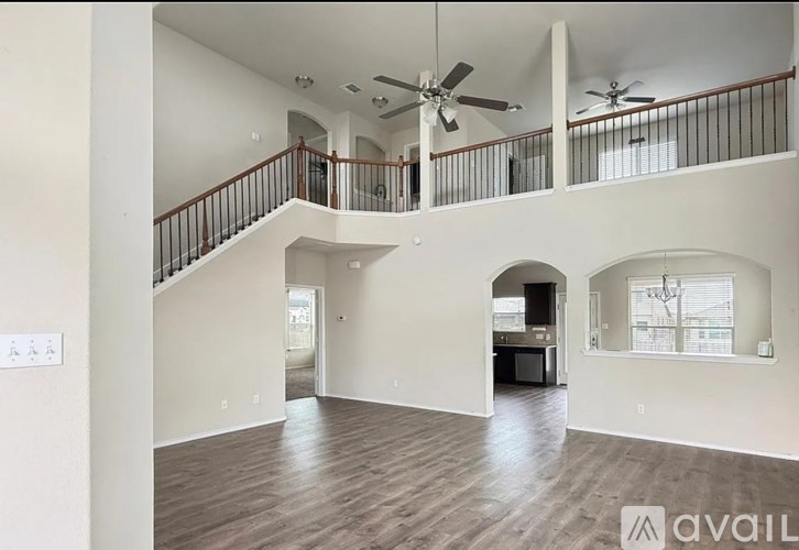 A spacious living room with a staircase and a ceiling fan.